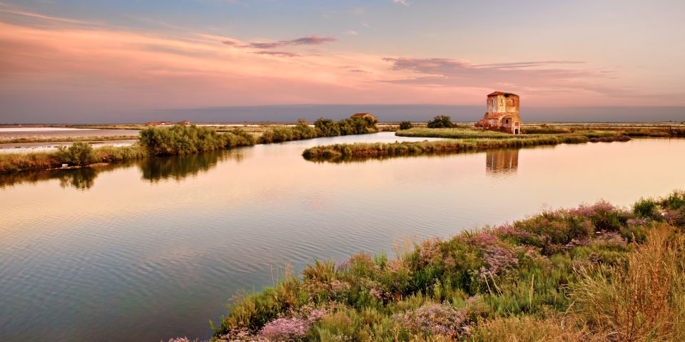 Abendlicht taucht die Lagunen bei Comacchio in warme Gold- und Rottöne. 