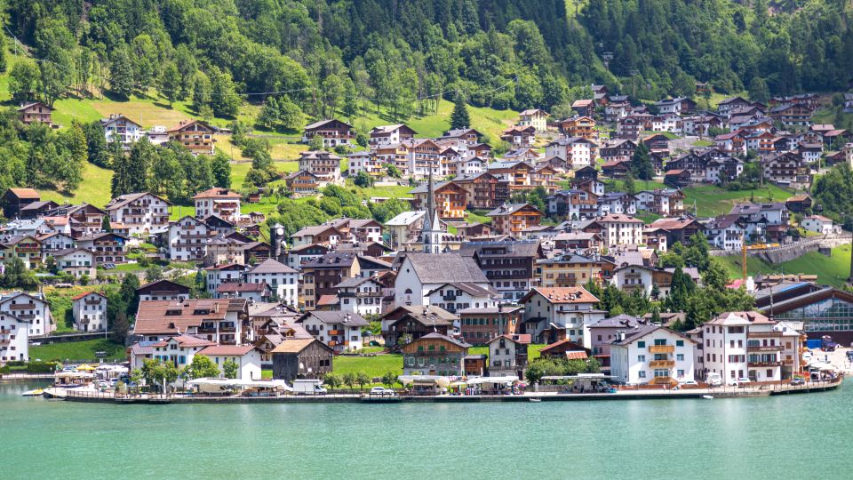 Im Herzen von Alleghe steht die malerische Kirche am Seeufer, umgeben von Dolomitenkulisse und spiegelndem Wasser.