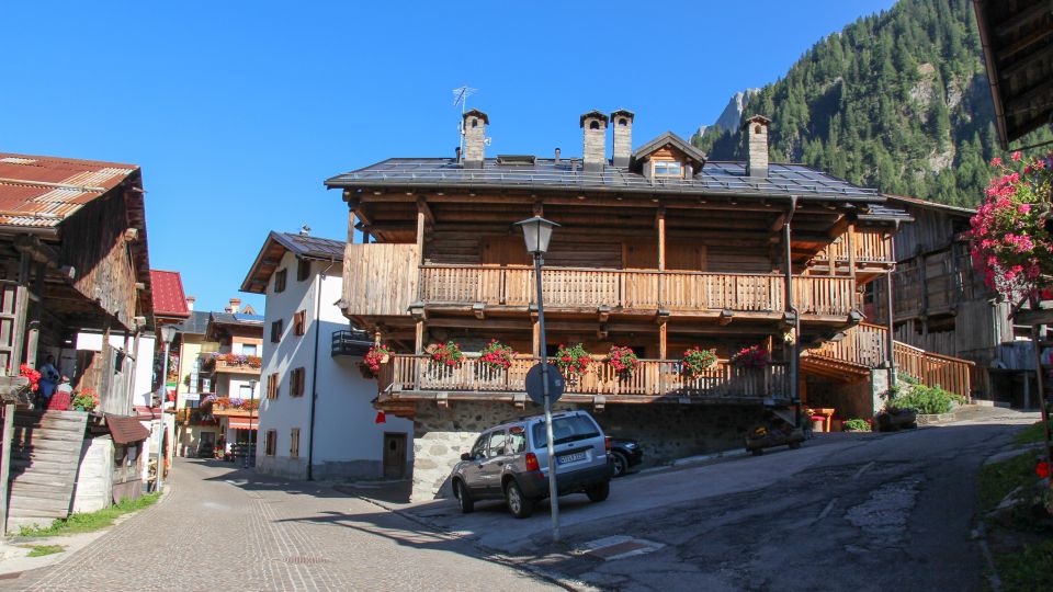 Die traditionellen Häuser von Rocca Pietore zeigen typische Dolomitenarchitektur mit Steinmauern, Holz und Schindeldächern.