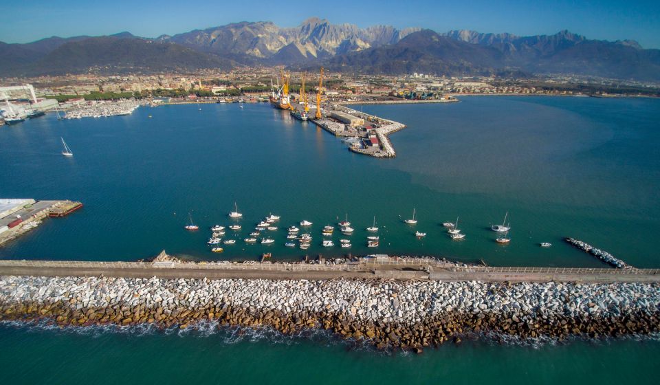 Ein Blick auf den Hafen von Marina di Carrara vor den Apuanischen Alpen verbindet maritime Atmosphäre mit Bergpanorama.