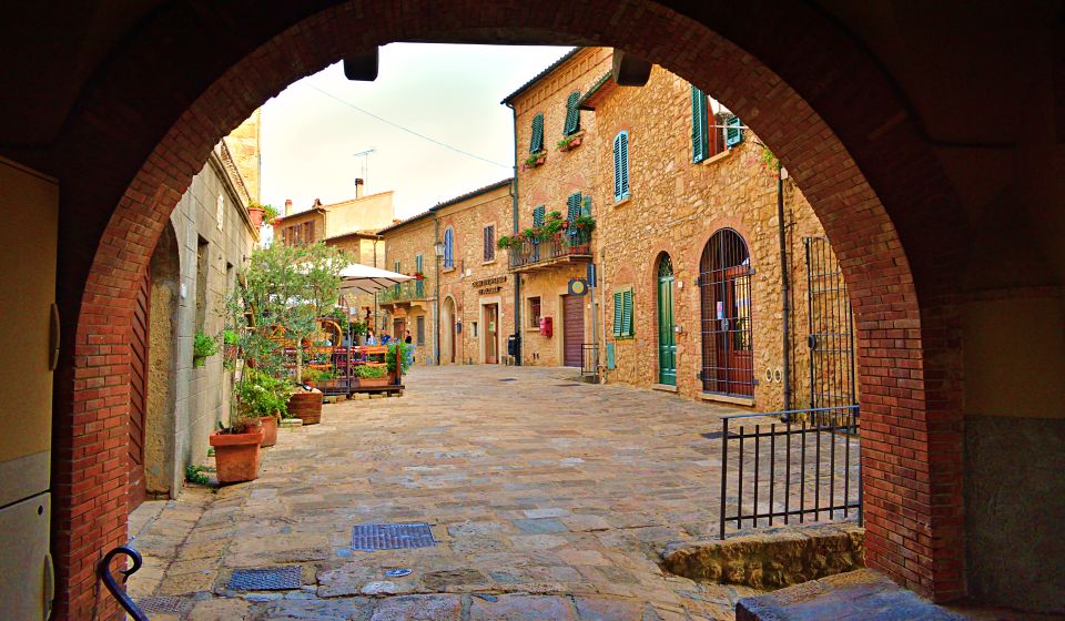 Die Steinhäuser leuchten in warmen Ocker- und Sandtönen, mit Terrakottadächern, Bögen und blumengeschmückten Fenstern.