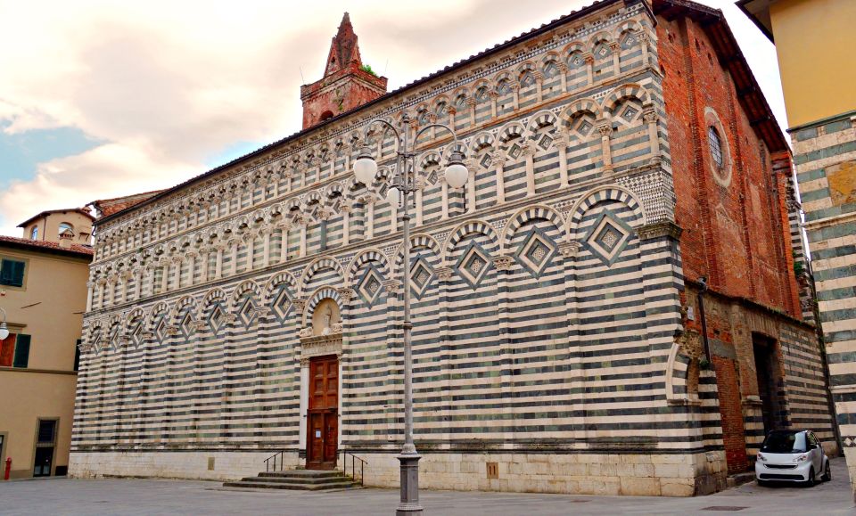 Die Außenfassade beeindruckt mit schwarz-weißem Marmor, rhythmischen Arkaden und klarer romanischer Strenge im Stadtbild