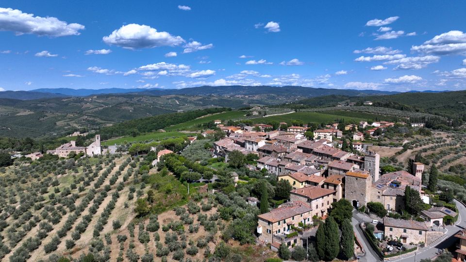 Drohnenblick über San Donato in Poggio zeigt den Hügelborgo, Steinmauern, Zypressen und weite Chiantihügel im Abendlicht.