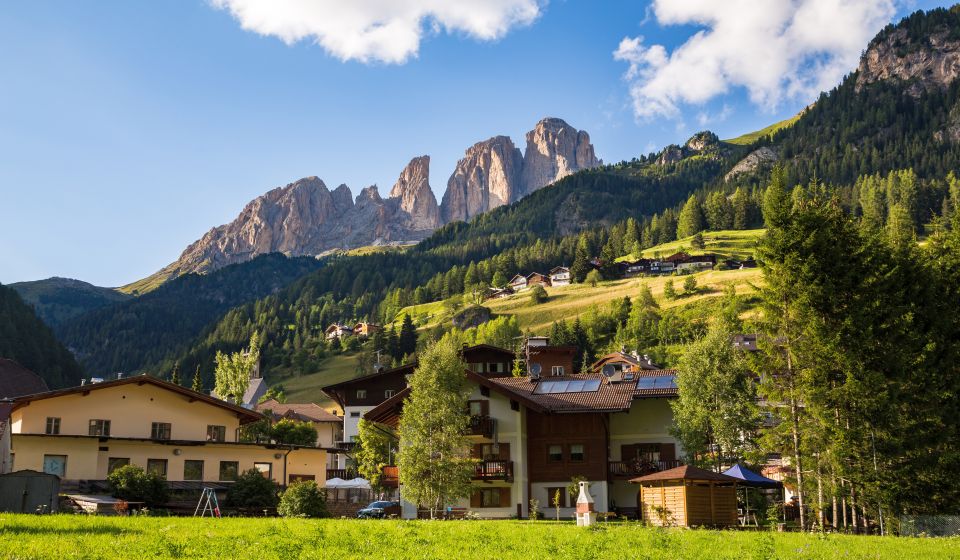 Campitello bei Sonnenuntergang: Die Dolomiten leuchten in warmen Farben und hüllen das Bergdorf in Magie – purer Zauber.