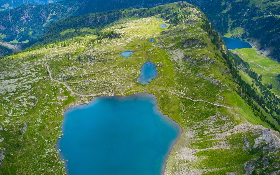 Drohnenblick auf die Seenplatte des Lago di Bombasel zeigt stille Wasserflächen, Feuchtwiesen und weite Hochlagen.