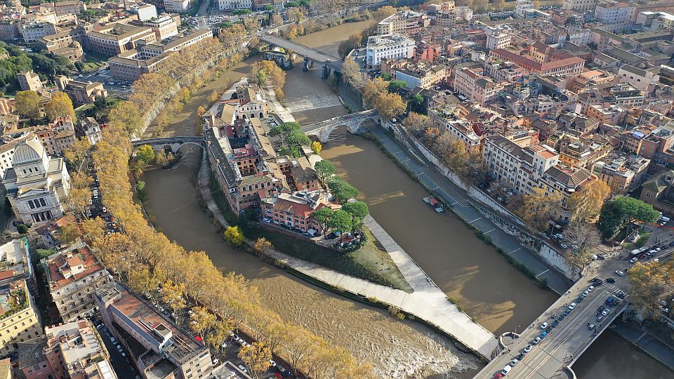 Aus der Luft zeigt sich die Isola Tiberina wie ein kleines Schiff im Tiber, eingerahmt von Brücken und den Dächern Roms.