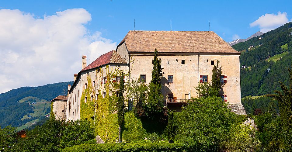 Schloss Schenna thront in aussichtsreicher Lage über Meran, umgeben von Weinbergen und Südtiroler Bergen.
